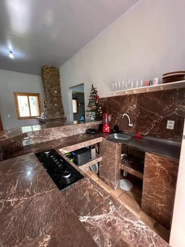 a kitchen with a granite counter top with a sink at Casa na beira do rio com Lareira in Itati