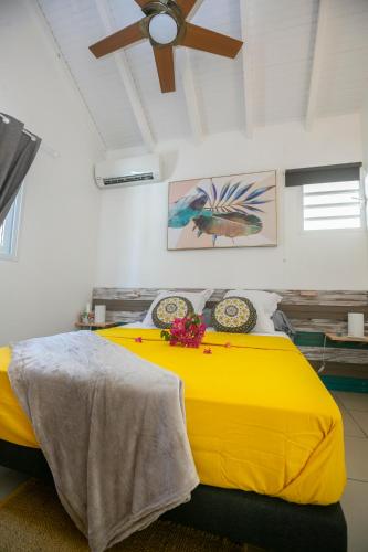 a bedroom with a yellow bed with a ceiling fan at Les VILLAS D'Ô in Saint-François