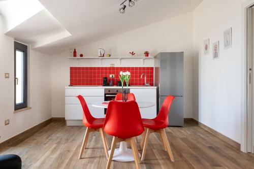 a dining room with red chairs and a table at Rosso Rubino - Mansarda Vista Lago a Marta in Marta