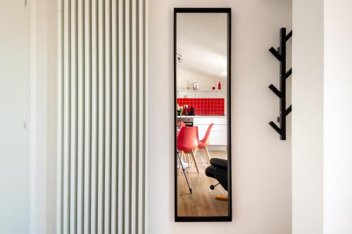 a hallway with a mirror and a red chair at Rosso Rubino - Mansarda Vista Lago a Marta in Marta