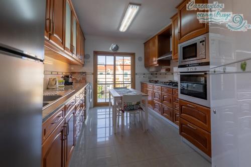 a large kitchen with wooden cabinets and white appliances at Carcavelos Ocean Breeze in Carcavelos
