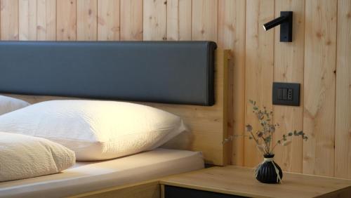 a bed with a pillow and a vase on a table at Grimmhof in Fiè