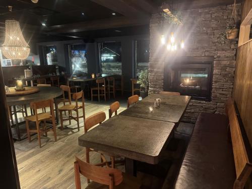 a restaurant with a fireplace and tables and chairs at Skogstad Hotel - Unike Hoteller in Hemsedal