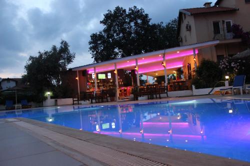 a swimming pool in front of a restaurant at night at Tunacan Hotel in Oludeniz