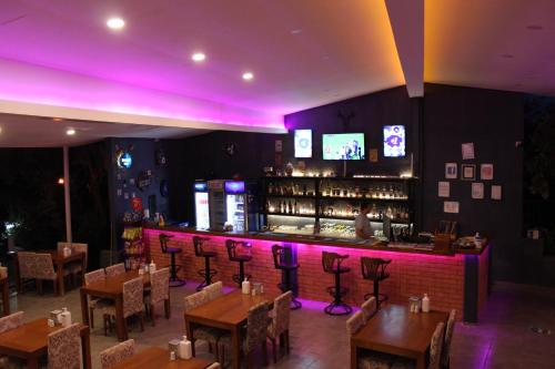 a restaurant with tables and a bar with purple lights at Tunacan Hotel in Oludeniz