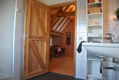 a bathroom with a wooden door and a sink at Erfgoed & Logies Den Heijkant in Moergestel