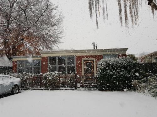 a house covered in snow with a car parked in front at Onder de Beukenboom in Nieuwe Pekela