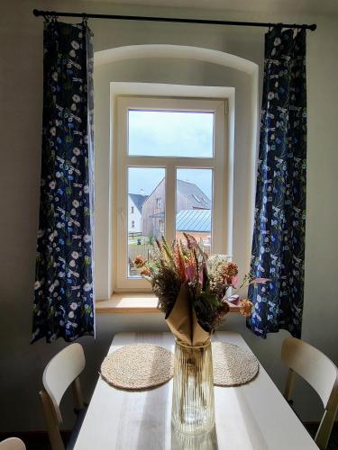 a vase of flowers on a table in front of a window at Velflík - ubytování v srdci Krušných hor in Abertamy