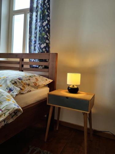 a lamp on a nightstand next to a bed with a window at Velflík - ubytování v srdci Krušných hor in Abertamy