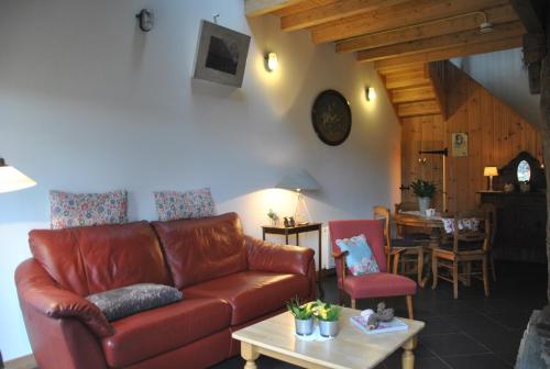a living room with a leather couch and a table at Erfgoed & Logies Den Heijkant in Moergestel