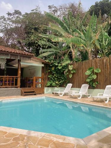 een zwembad met twee stoelen en een hek bij Pousada Banana Verde in Ilhabela