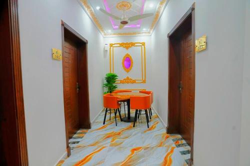 a dining room with a table and orange chairs at The Lahore Guest House in Lahore