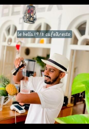a man in a hat is making a drink at le bella1912 in Galle