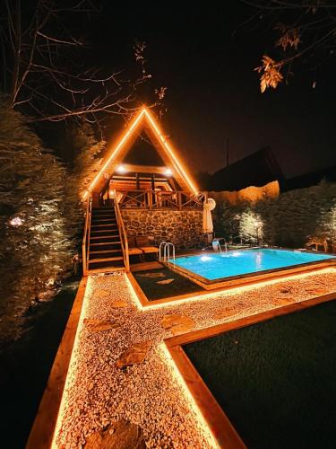 a swimming pool with a deck and a house with lights at Merce Bungalov in Sapanca