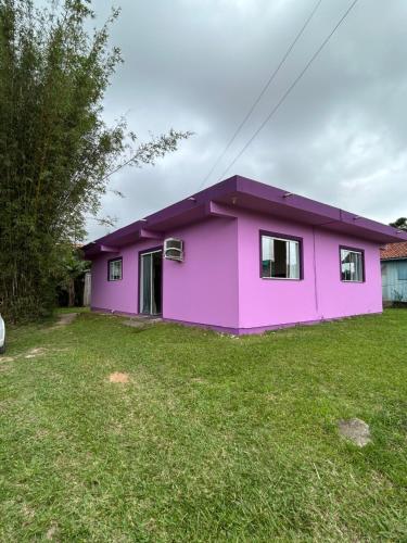 a pink house with a green yard at Casa da Laura - Praia Garopaba in Garopaba