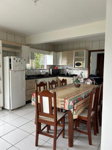 a kitchen with a table and chairs and a refrigerator at Casa da Laura - Praia Garopaba in Garopaba