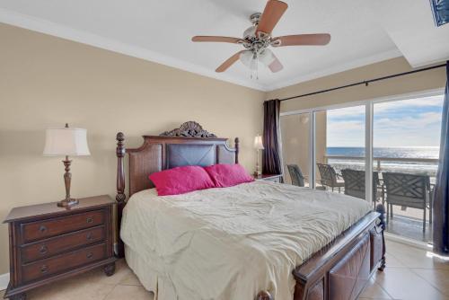 1 dormitorio con 1 cama con almohadas rosas y ventilador de techo en Emerald Isle unit 202, en Pensacola Beach