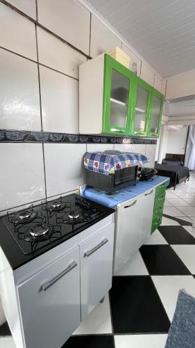a kitchen with a stove and green cabinets at Cantinho do sossego Arraial do cabo - Prainha in Arraial do Cabo
