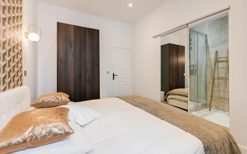 a bedroom with a white bed with brown pillows at Appart Élégance in Lyon