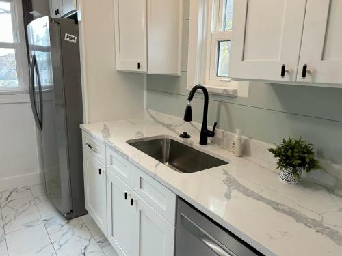a white kitchen with a sink and a refrigerator at The Urban Nest – Your St. Louis City Retreat! in Saint Louis