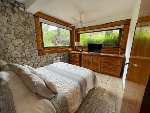 a bedroom with a bed and a stone wall at Cabañas en Valeria del Mar in Carilo