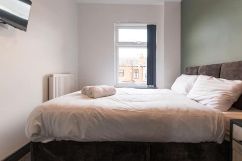 a bedroom with a large white bed with a window at Urmston House in Leigh