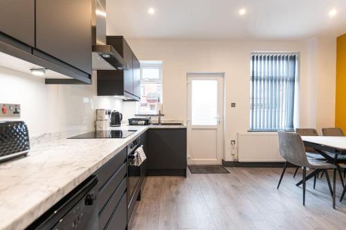 a kitchen with a table and a dining room at Urmston House in Leigh