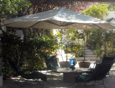 a table and chairs under an umbrella in a yard at Los Milagros Hotel in Cabo San Lucas