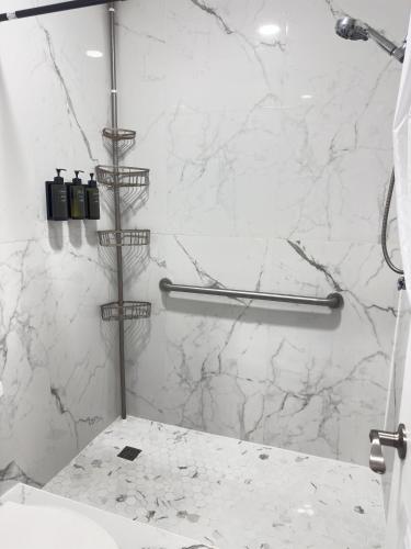 a bathroom with a shower with white marble walls at Sunshine Inn & Suites Venice, Florida in Venice