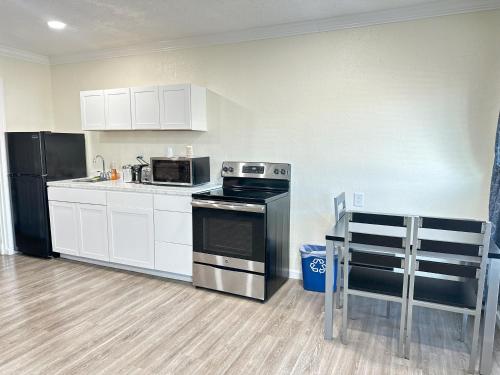 a kitchen with white cabinets and a black refrigerator at Sunshine Inn & Suites Venice, Florida in Venice