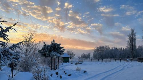a snow covered field with a sunset in the background at Farma František in Stachy