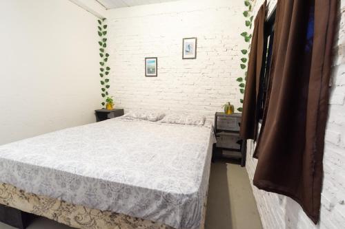 a bedroom with a bed and a white brick wall at Pipa Surf House in Pipa