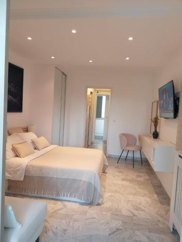 une chambre blanche avec deux lits et une chaise dans l'établissement Palm beach Cannes La Brise, à Cannes