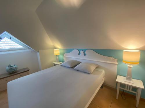 - une chambre avec un grand lit blanc et deux lampes dans l'établissement Appartement, 2 chambres, Terrasse vue mer, très calme, Piscine premium, accès direct aux plages, restaurants, Village Vacances, à Sainte-Luce