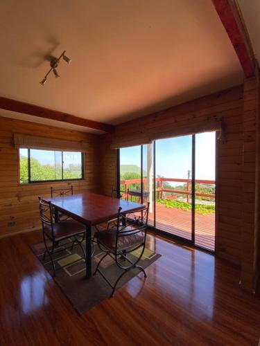 a dining room with a table and chairs and a balcony at Cabañas Cerro Tacna in Maitencillo
