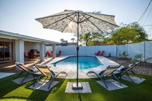 a patio with an umbrella and chairs and a pool at Scottsdale Osborn in Scottsdale