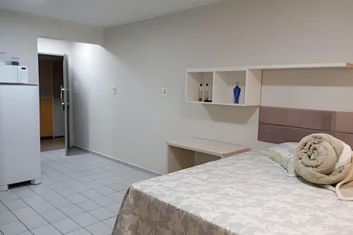 a bedroom with a bed and a kitchen with a refrigerator at Apto 215 Centro Nucleo Bandeirante in Núcleo Bandeirante