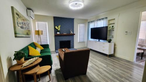 a living room with a green couch and a television at LAX House Near SoFi Stadium, Intuit Dome, YouTube Theater, The Kia Forum, Beaches in Inglewood
