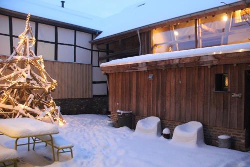 a christmas tree in the snow next to a building at fantastische vakwerk boerderij nabij Maastricht in Banholt