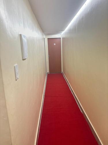 a corridor with a red carpet and a red door at H one Hotel in Goiânia