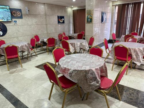 a room with tables and chairs with red chairs at فندق غالب المشاعر in Miná