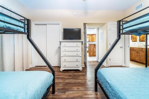 a bedroom with two bunk beds and a tv at Boardwalk 1502 in Panama City Beach