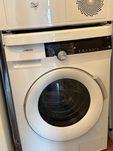 a washing machine with a microwave on top of it at Appt Vue Place de Toscane - 4min Disneyland-PARIS in Serris