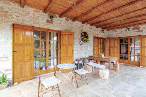 a patio with a table and chairs and a wooden ceiling at Stone Mountainhouse near Kalavryta, North Peloponnese, Greece in Dhoumená