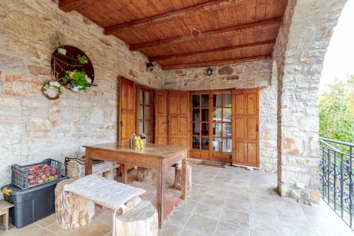 a patio with a wooden table and a wooden ceiling at Stone Mountainhouse near Kalavryta, North Peloponnese, Greece in Dhoumená