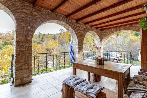 a patio with a wooden table and a balcony at Stone Mountainhouse near Kalavryta, North Peloponnese, Greece in Dhoumená