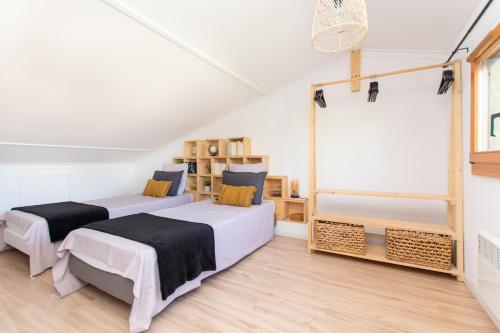 two beds in a room with white walls and wooden floors at Magnifique villa avec piscine et climatisation in Lombez