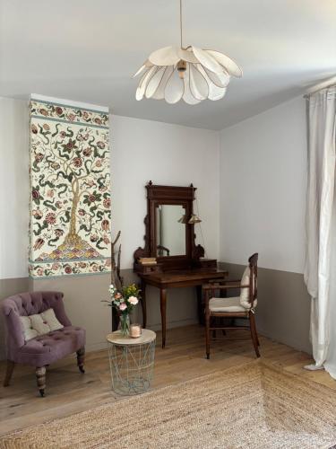 a living room with a chair and a table and a mirror at Le logis blanc bed&breakfast in Coursan