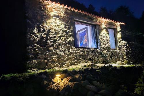 a person looking out a window of a stone building at night at cabaña do rei in Betán