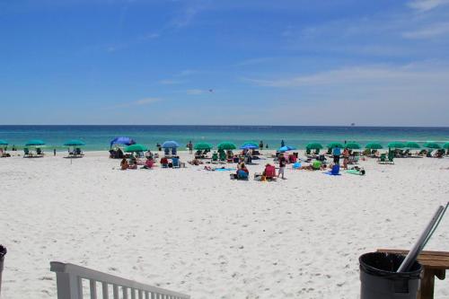 a group of people sitting on a beach with umbrellas at Pelican Beach Terrace 805 in Destin
